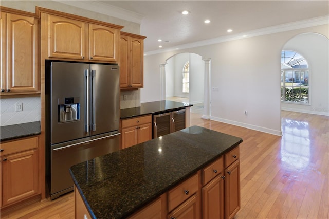 kitchen featuring stainless steel fridge with ice dispenser, crown molding, dark stone counters, and tasteful backsplash