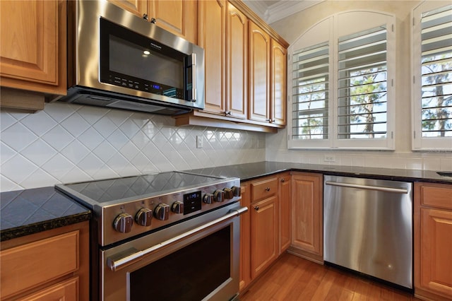 kitchen with appliances with stainless steel finishes, backsplash, light hardwood / wood-style floors, and crown molding