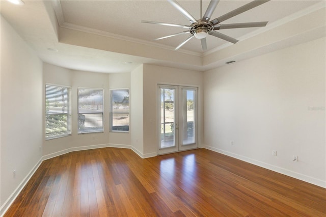 empty room with ceiling fan, dark hardwood / wood-style floors, a raised ceiling, and crown molding