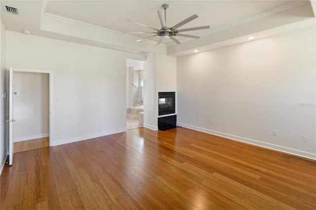 unfurnished living room featuring hardwood / wood-style floors, ceiling fan, crown molding, and a tiled fireplace