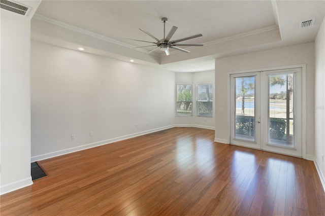 unfurnished room featuring ceiling fan, a raised ceiling, wood-type flooring, and french doors