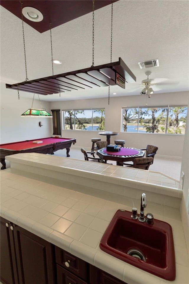 kitchen featuring dark brown cabinetry, ceiling fan, sink, billiards, and tile countertops