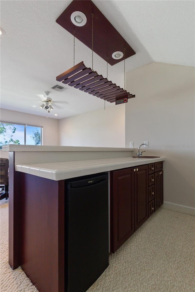 kitchen with kitchen peninsula, ceiling fan, sink, and fridge