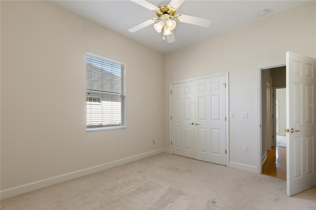 unfurnished bedroom with ceiling fan, a closet, and light carpet