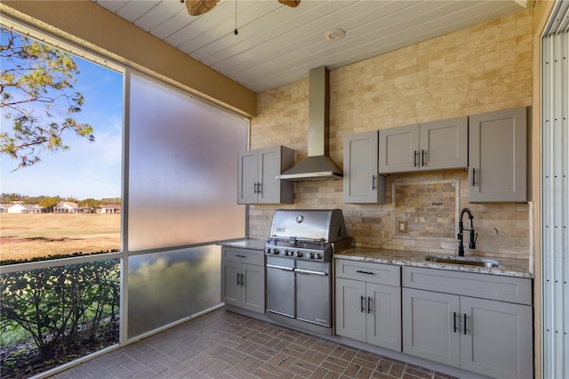 kitchen featuring backsplash, wall chimney exhaust hood, gray cabinetry, and sink