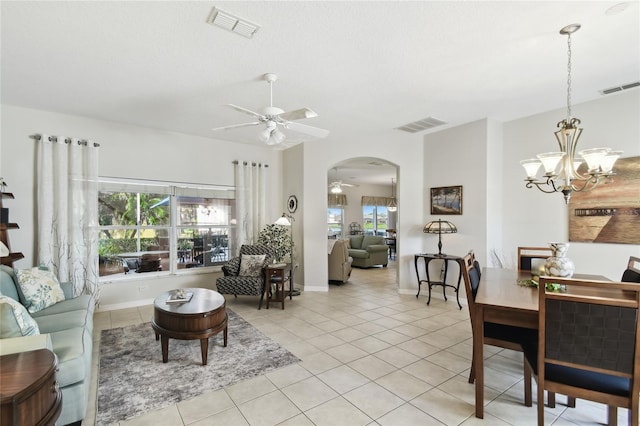 tiled living room with ceiling fan with notable chandelier and a wealth of natural light