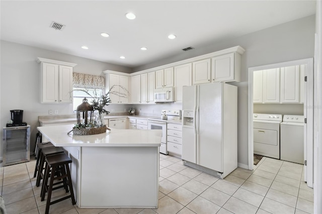 kitchen featuring separate washer and dryer, a center island, white cabinets, and white appliances