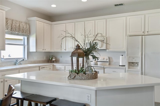 kitchen featuring white cabinets, white appliances, a kitchen island, and sink