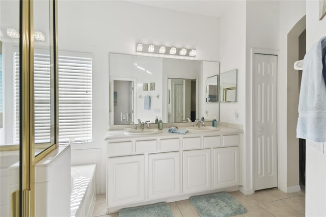 bathroom featuring tile patterned flooring, vanity, a healthy amount of sunlight, and a washtub