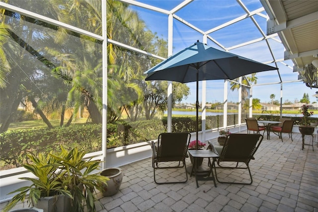 view of patio featuring a water view and glass enclosure