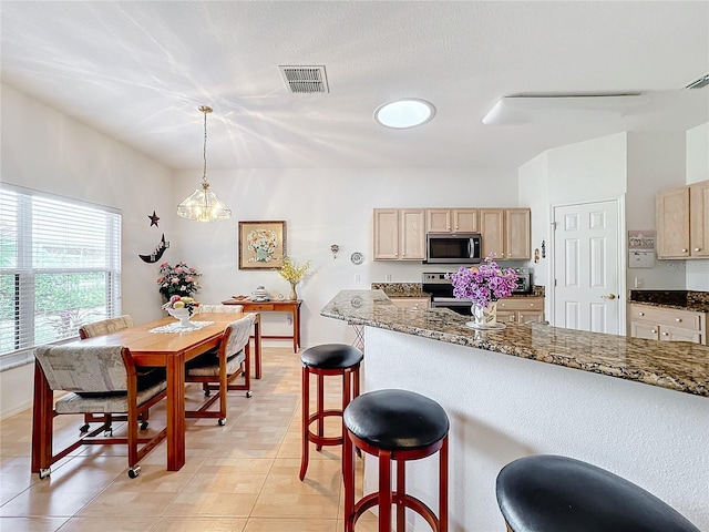 kitchen with pendant lighting, light brown cabinets, light tile patterned floors, and stainless steel appliances