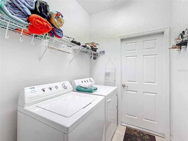 clothes washing area with washing machine and dryer and light tile patterned floors