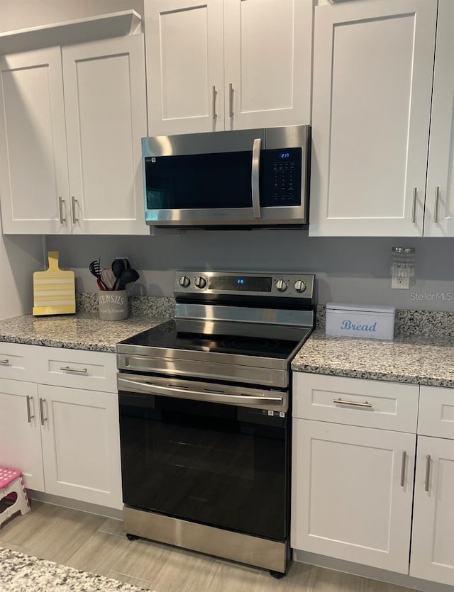 kitchen featuring white cabinets, light stone counters, and stainless steel appliances