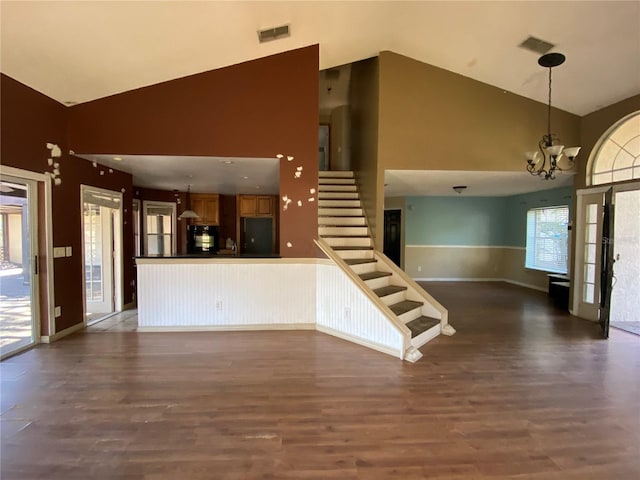 unfurnished living room with dark hardwood / wood-style flooring, high vaulted ceiling, and a chandelier