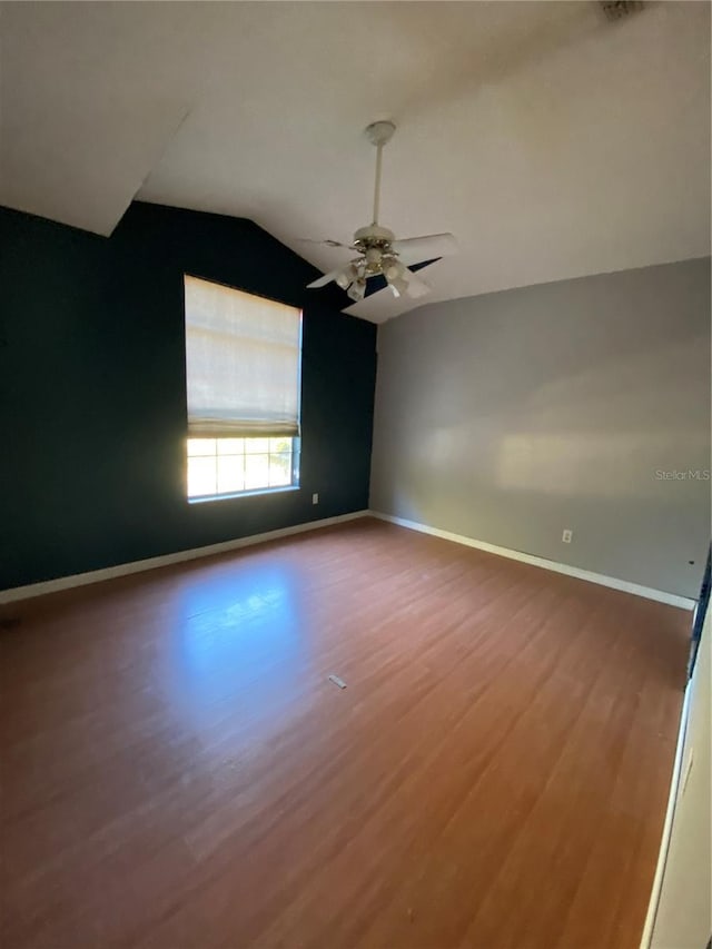 empty room with ceiling fan, wood-type flooring, and vaulted ceiling