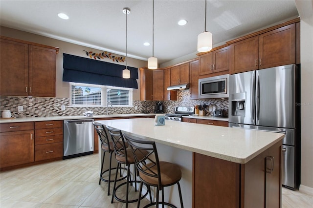 kitchen featuring light stone countertops, appliances with stainless steel finishes, sink, decorative light fixtures, and a center island