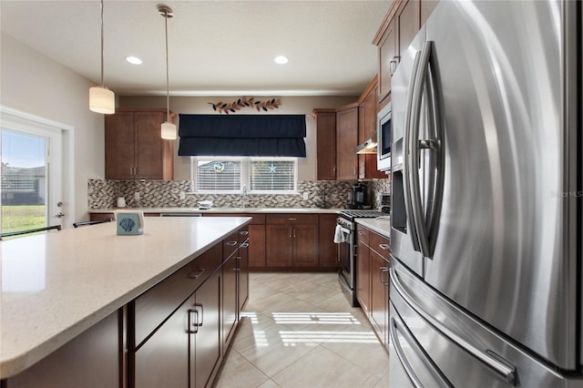 kitchen with light stone countertops, appliances with stainless steel finishes, decorative backsplash, light tile patterned floors, and pendant lighting