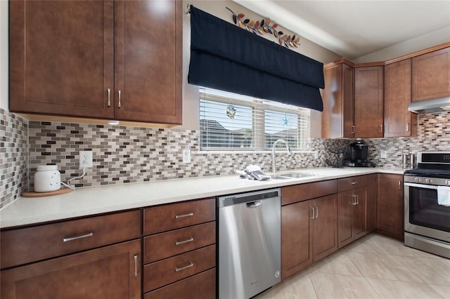 kitchen featuring sink, tasteful backsplash, range hood, light tile patterned flooring, and appliances with stainless steel finishes