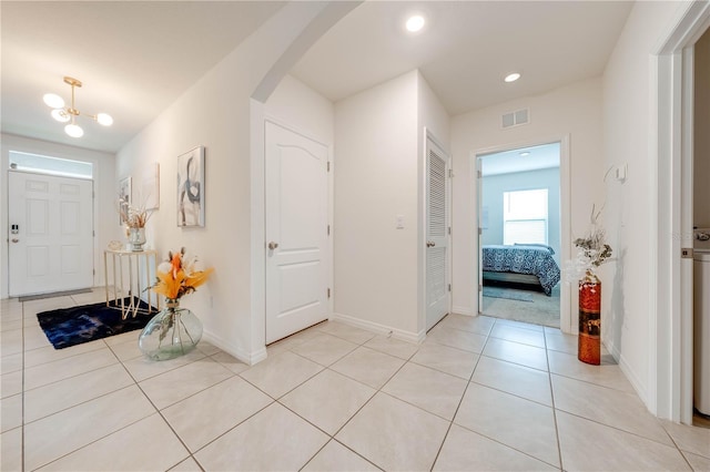 foyer featuring light tile patterned floors and an inviting chandelier