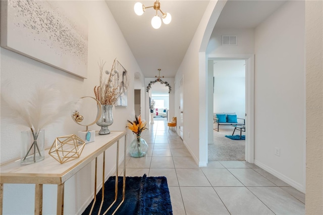 corridor featuring light tile patterned flooring and an inviting chandelier