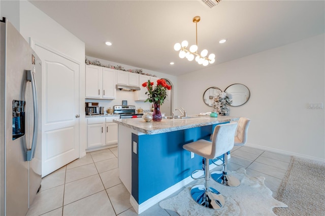 kitchen featuring a kitchen island with sink, white cabinets, light tile patterned floors, decorative light fixtures, and stainless steel appliances