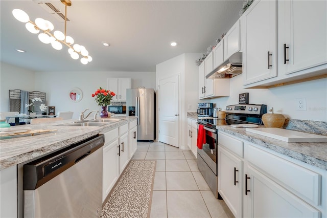 kitchen with appliances with stainless steel finishes, sink, light tile patterned floors, white cabinetry, and range hood