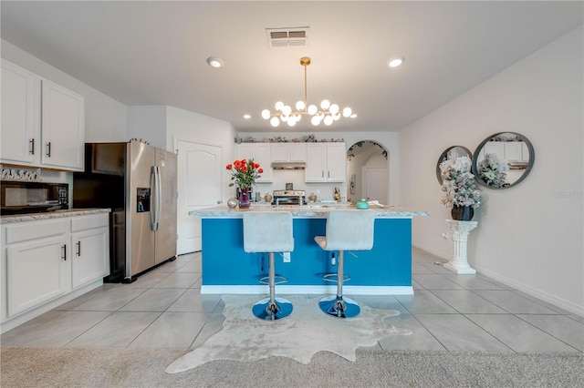 kitchen featuring white cabinets, hanging light fixtures, light tile patterned floors, an island with sink, and stainless steel appliances