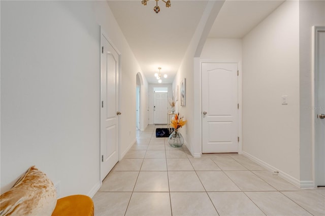 hallway featuring a notable chandelier and light tile patterned floors