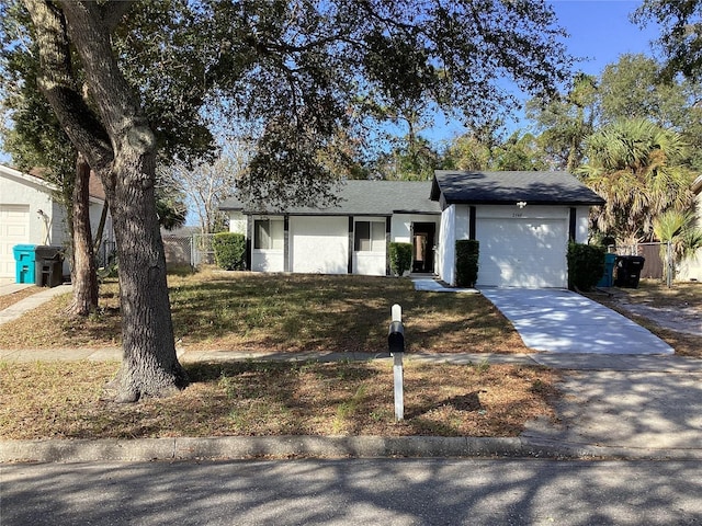 view of front facade with a garage, fence, concrete driveway, and stucco siding