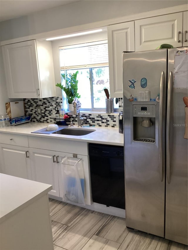 kitchen featuring white cabinetry, black dishwasher, light countertops, decorative backsplash, and stainless steel fridge