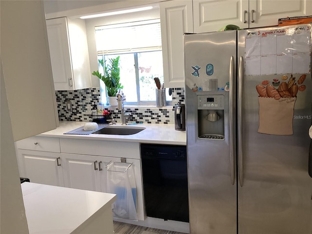 kitchen featuring a sink, white cabinets, black dishwasher, stainless steel refrigerator with ice dispenser, and decorative backsplash