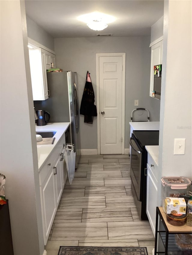 kitchen featuring white cabinets, stainless steel electric stove, and light countertops