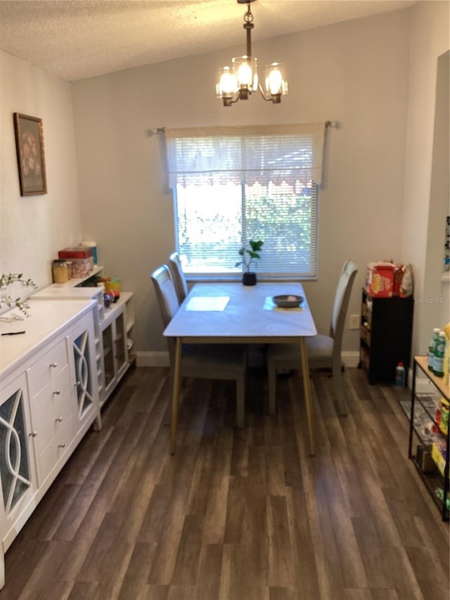 dining area featuring dark wood-style floors, a notable chandelier, a textured ceiling, and baseboards