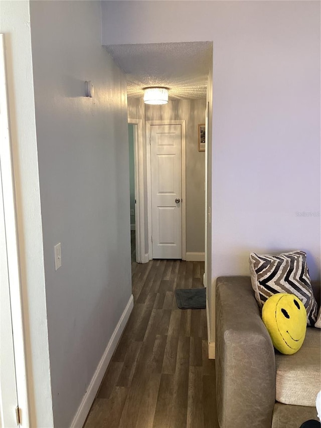 hallway featuring dark wood finished floors and baseboards