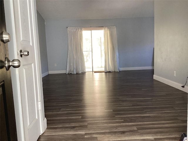 spare room featuring dark wood-style flooring and baseboards