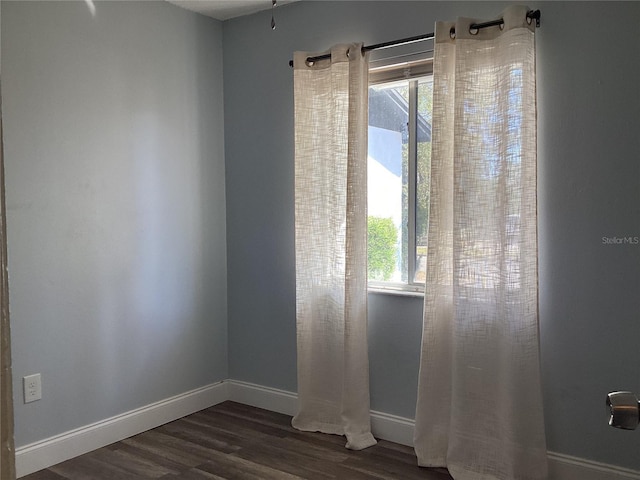 unfurnished room featuring dark wood-style floors and baseboards