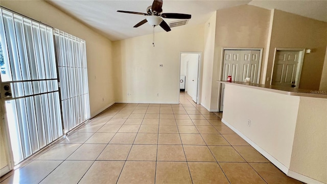 spare room with a ceiling fan, lofted ceiling, and light tile patterned floors