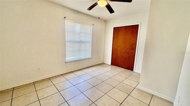 unfurnished bedroom featuring a closet, light tile patterned flooring, ceiling fan, and baseboards