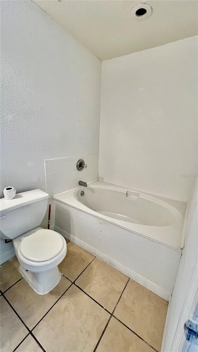 bathroom featuring tile patterned flooring, toilet, and a bath