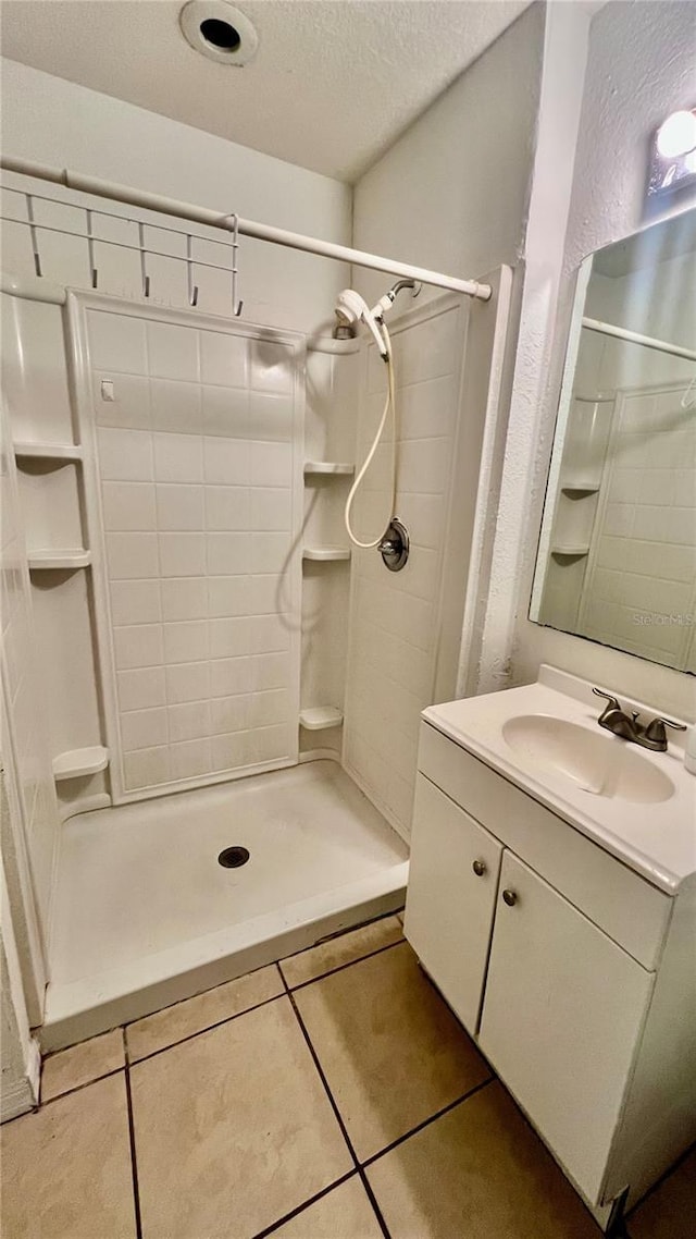 bathroom with a textured ceiling, a stall shower, tile patterned flooring, and vanity