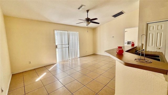 interior space featuring ceiling fan, light tile patterned flooring, lofted ceiling, and visible vents