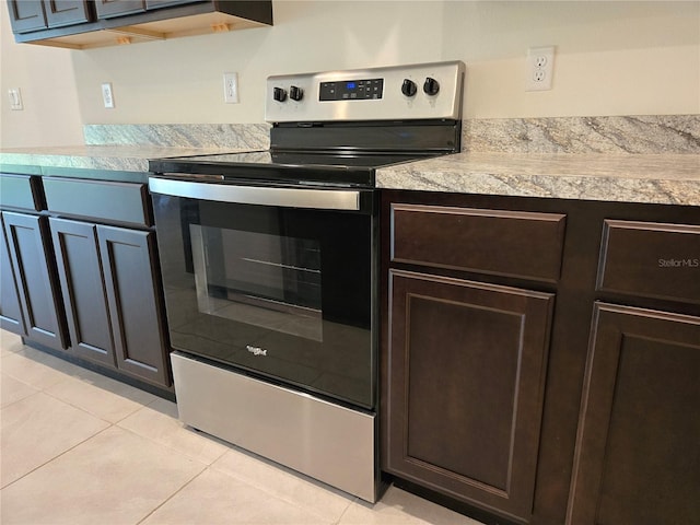 kitchen featuring stainless steel electric stove, dark brown cabinets, and light tile patterned flooring