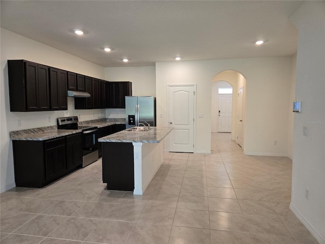 kitchen featuring sink, stainless steel appliances, light stone counters, a center island with sink, and light tile patterned flooring