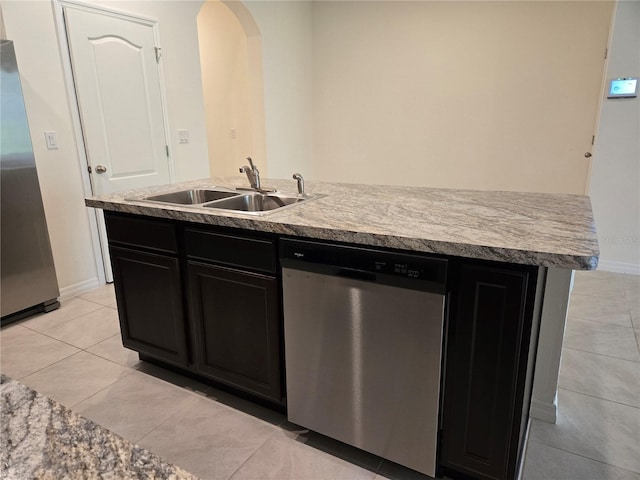 kitchen featuring sink, light tile patterned floors, stainless steel appliances, and an island with sink