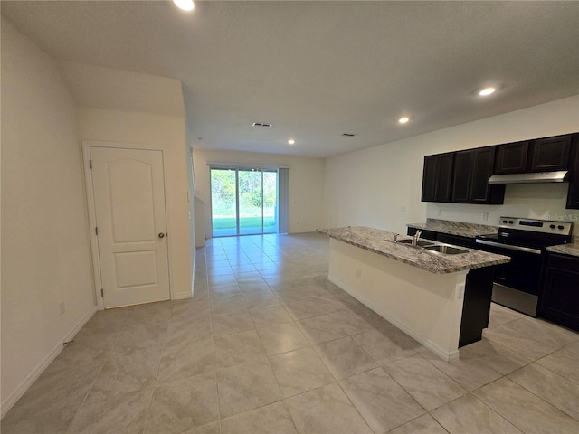 kitchen featuring light stone counters, sink, an island with sink, stainless steel electric range oven, and light tile patterned flooring