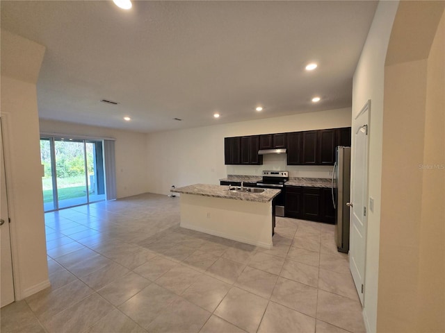 kitchen with a kitchen island with sink, light tile patterned floors, stainless steel appliances, and light stone counters