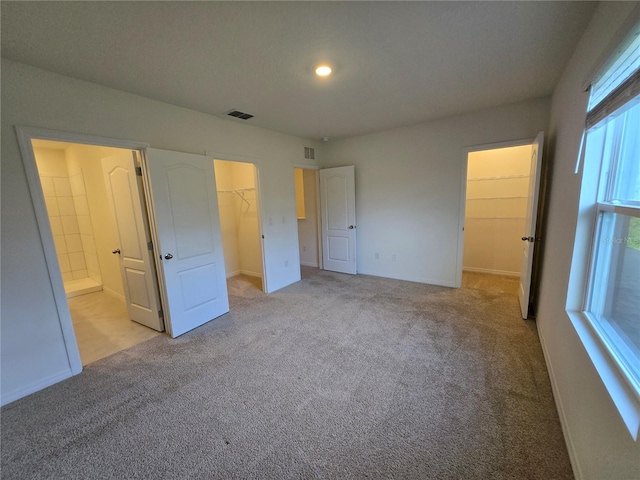 unfurnished bedroom featuring a walk in closet, light colored carpet, and a closet