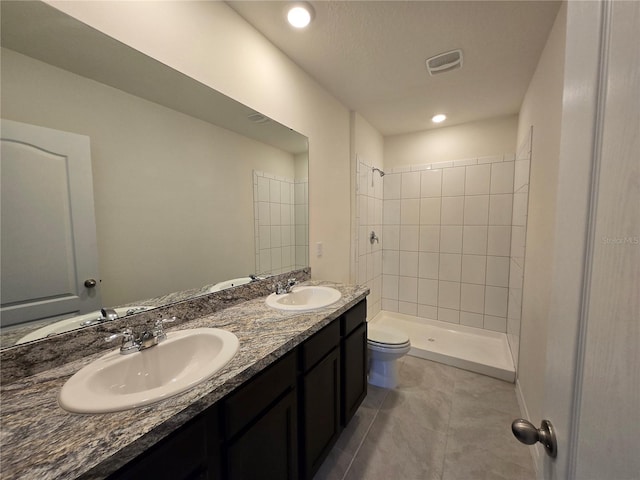 bathroom featuring tiled shower, vanity, tile patterned flooring, and toilet