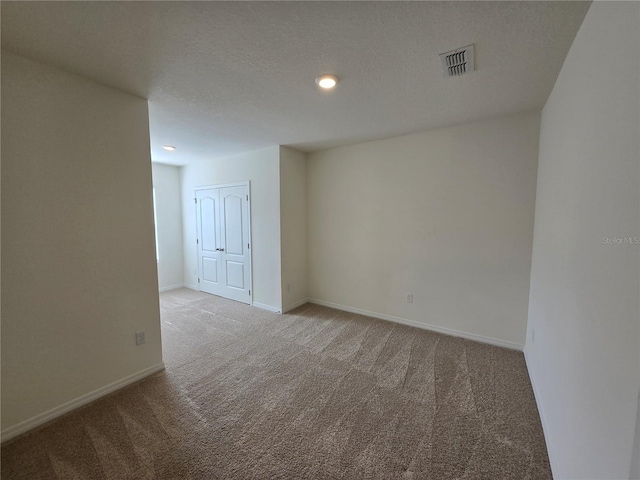 spare room with light carpet and a textured ceiling