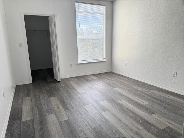 interior space featuring wood-type flooring, a walk in closet, a closet, and multiple windows